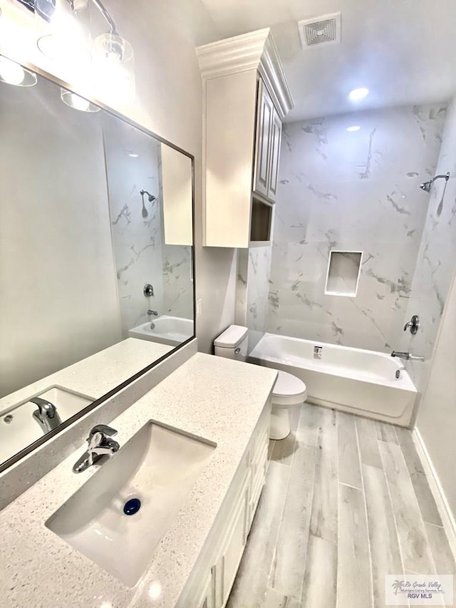 bathroom featuring toilet, wood finished floors, visible vents, vanity, and bathing tub / shower combination