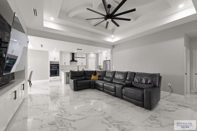 living room with a raised ceiling and ceiling fan