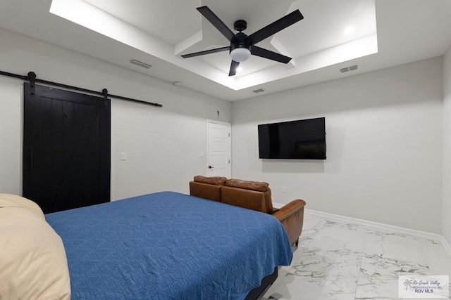 bedroom featuring ceiling fan, a barn door, and a raised ceiling