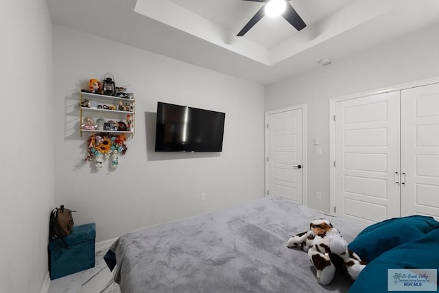 bedroom with ceiling fan, a raised ceiling, and a closet