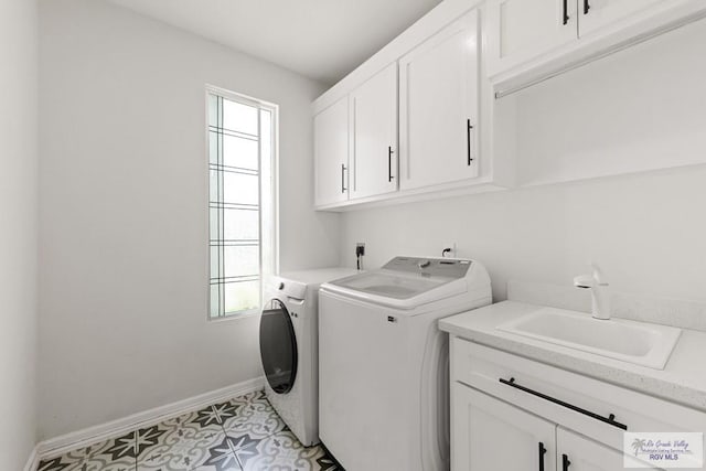 laundry room with cabinets, light tile patterned floors, sink, and washing machine and dryer