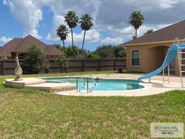 view of swimming pool with a yard and a water slide