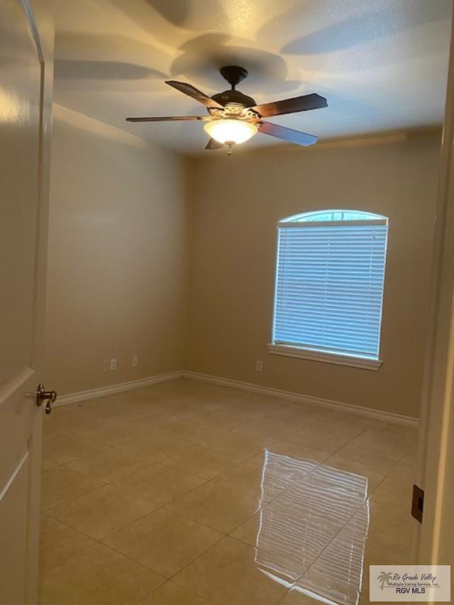 tiled spare room featuring ceiling fan