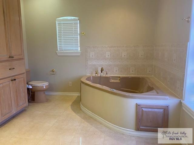 bathroom with tile patterned flooring, a washtub, and toilet