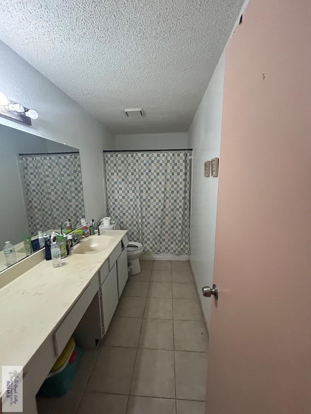 bathroom featuring tile patterned floors, walk in shower, vanity, a textured ceiling, and toilet