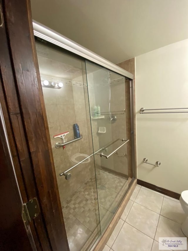 bathroom with tile patterned floors, toilet, and a shower with shower door