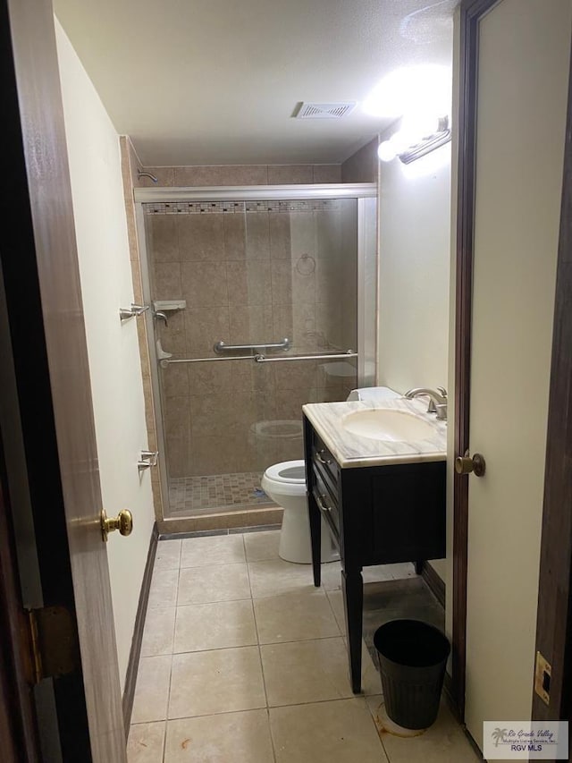 bathroom with tile patterned floors, vanity, toilet, and a shower with shower door