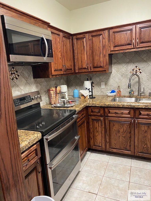 kitchen featuring tasteful backsplash, light stone countertops, sink, and stainless steel appliances