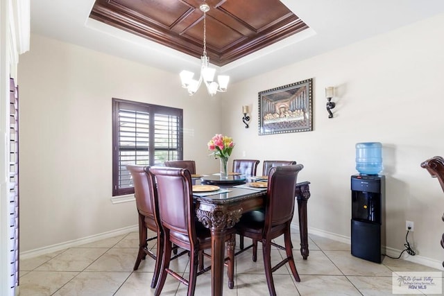 tiled dining space featuring crown molding, a tray ceiling, and a chandelier