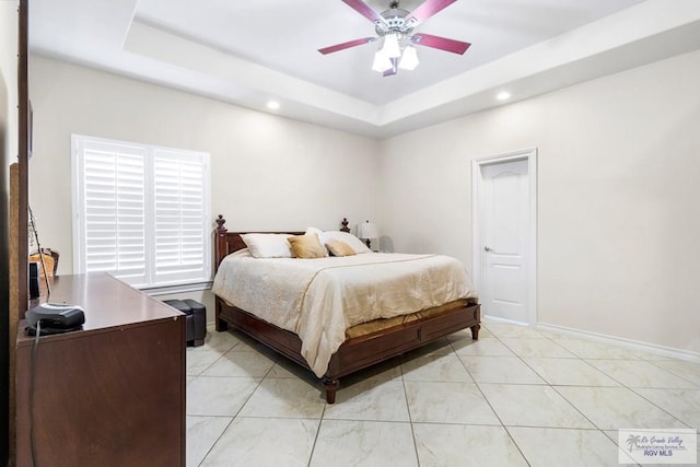 bedroom with ceiling fan and a raised ceiling