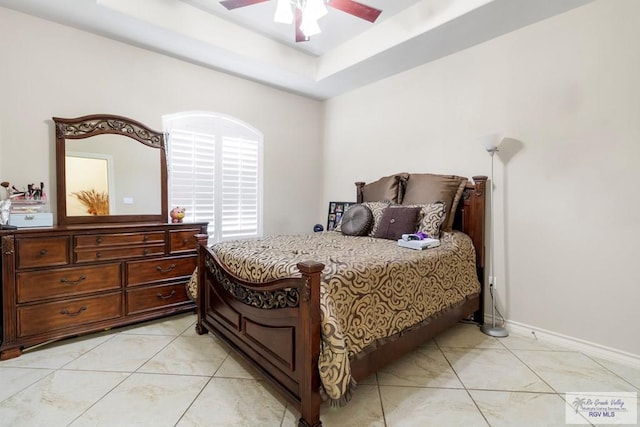 bedroom featuring ceiling fan, light tile patterned floors, and a tray ceiling