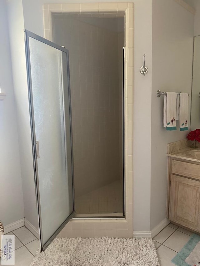 bathroom with tile patterned floors, a shower with door, and vanity