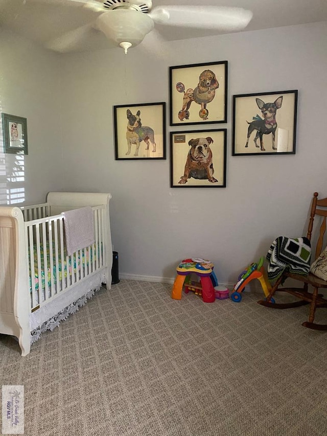 carpeted bedroom featuring ceiling fan and a nursery area