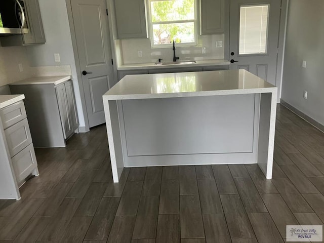 2914 Brushy Ct, Harlingen, TX 78552 - kitchen featuring stainless steel microwave, wood finish floors, a kitchen island, and decorative backsplash