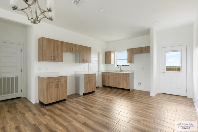 kitchen with hardwood / wood-style floors, pendant lighting, a wealth of natural light, and a notable chandelier