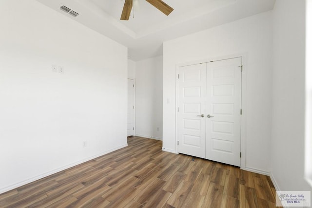 unfurnished bedroom featuring dark hardwood / wood-style floors, ceiling fan, and a closet