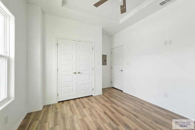 unfurnished bedroom with electric panel, ceiling fan, a closet, and light wood-type flooring