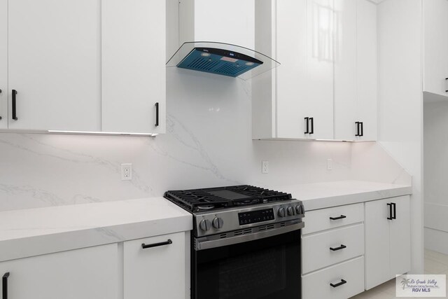 kitchen featuring backsplash, white cabinets, stainless steel stove, and wall chimney range hood