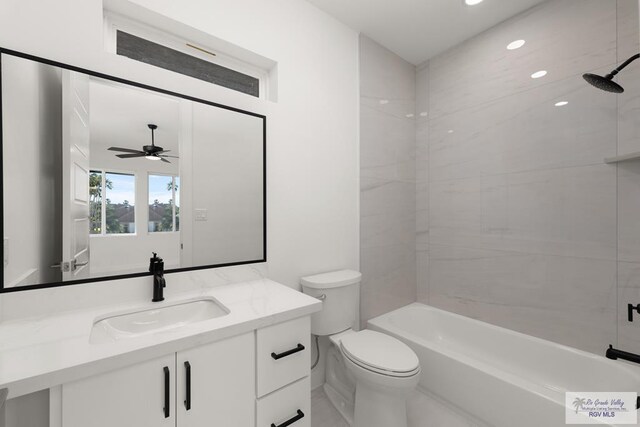 full bathroom featuring tiled shower / bath, vanity, toilet, and ceiling fan