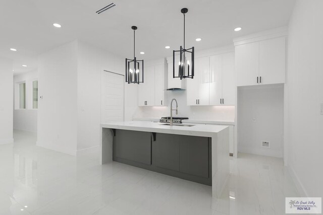 kitchen featuring sink, white cabinets, and pendant lighting