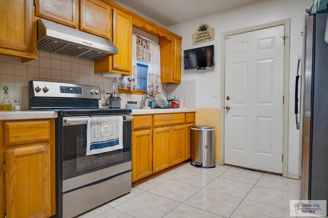 kitchen featuring backsplash, ventilation hood, stainless steel appliances, and light tile patterned flooring