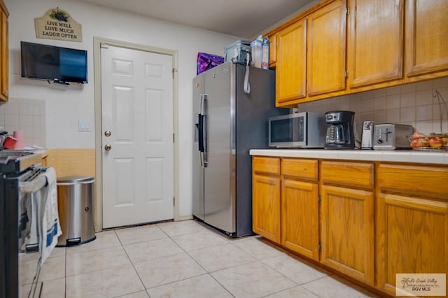 kitchen featuring backsplash, light tile patterned floors, and stainless steel appliances