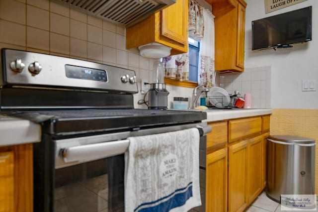 kitchen featuring ventilation hood, light tile patterned flooring, stainless steel electric range oven, and backsplash