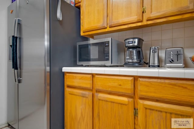 kitchen featuring decorative backsplash, tile counters, and appliances with stainless steel finishes