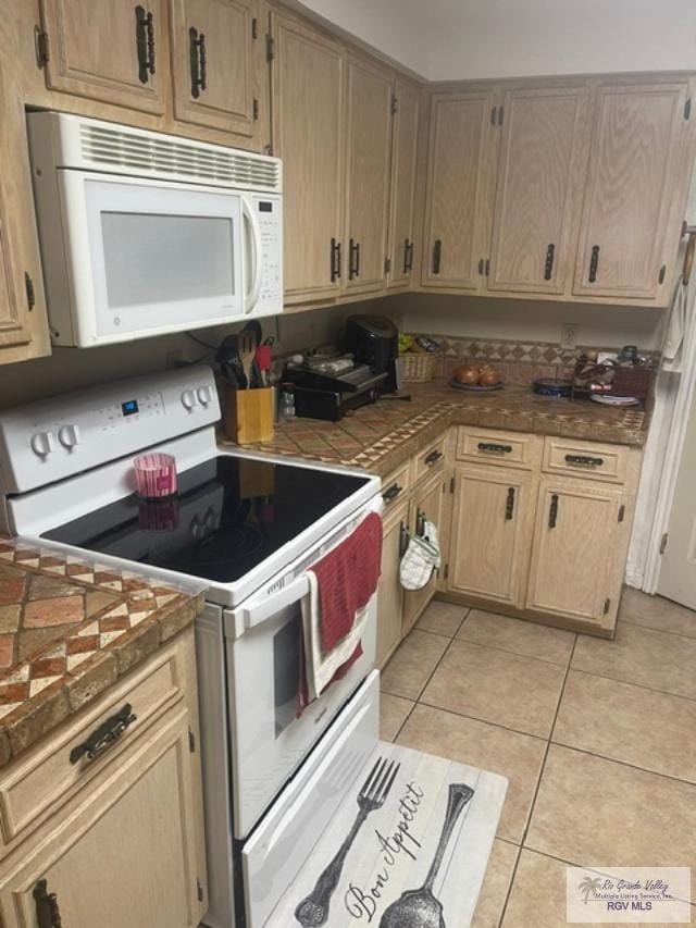 kitchen with light brown cabinetry, white appliances, and light tile patterned flooring