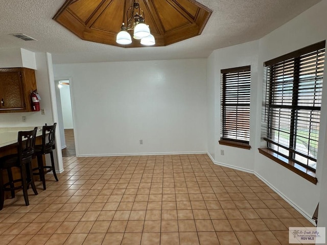 dining area featuring light tile patterned floors, a textured ceiling, and a notable chandelier