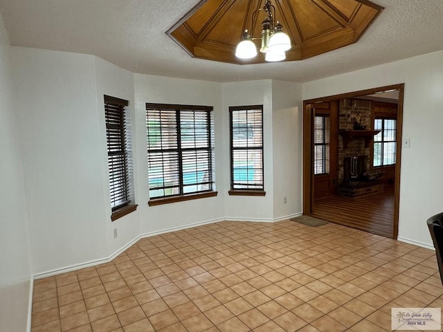 unfurnished room with a textured ceiling, light hardwood / wood-style floors, a fireplace, and a chandelier