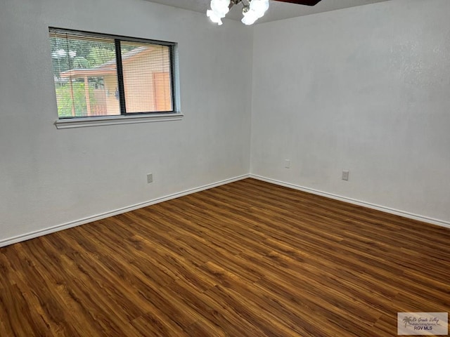 unfurnished room with dark hardwood / wood-style floors and an inviting chandelier