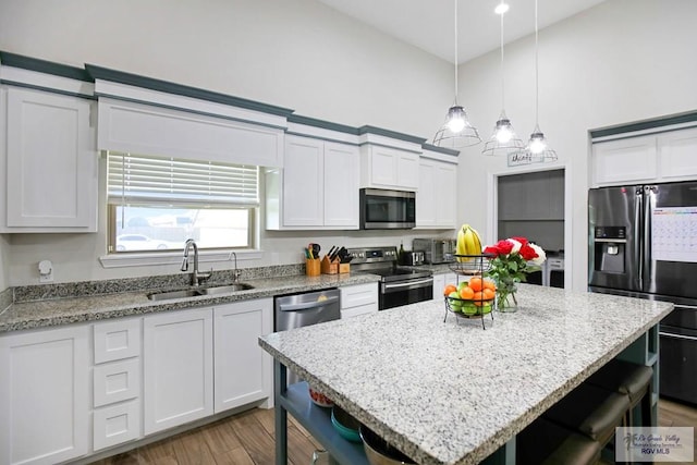 kitchen featuring white cabinetry, a center island, sink, appliances with stainless steel finishes, and a breakfast bar area