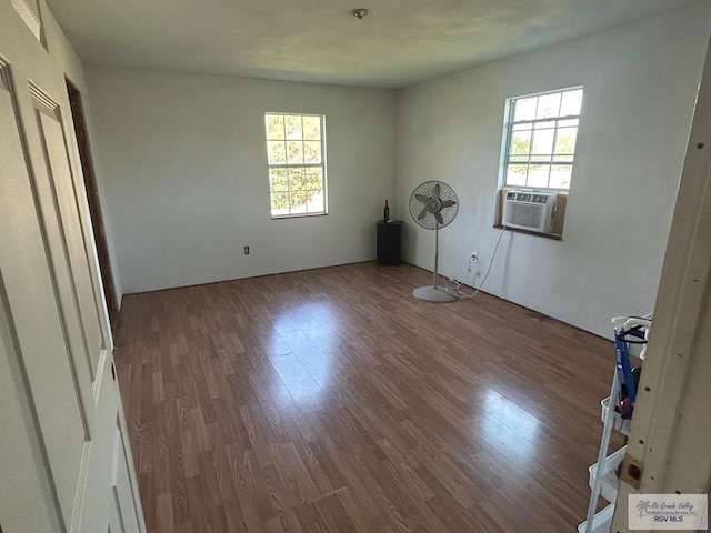 unfurnished bedroom with hardwood / wood-style flooring, cooling unit, and multiple windows