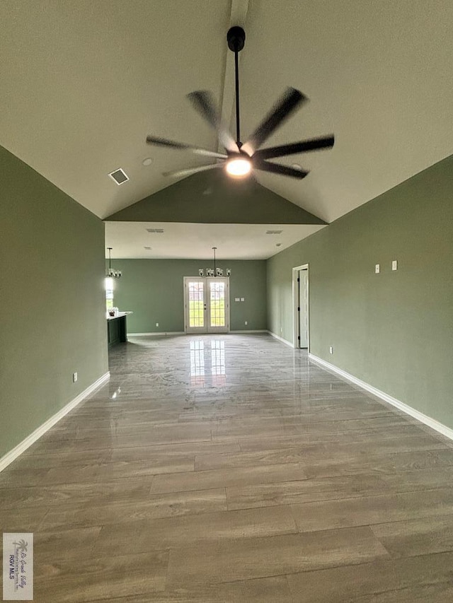 empty room featuring wood-type flooring, french doors, and vaulted ceiling