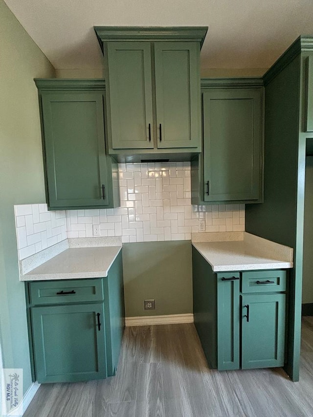 kitchen featuring tasteful backsplash, wood-type flooring, and green cabinetry