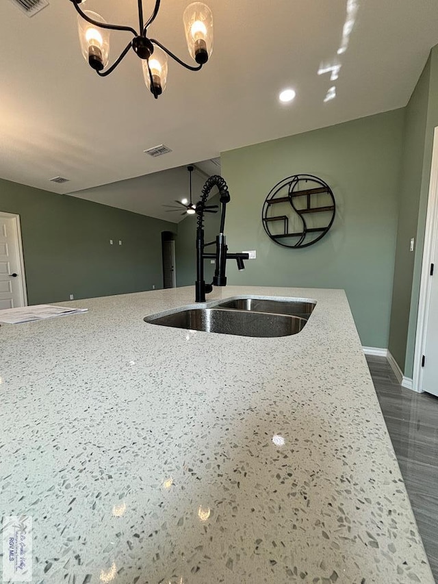 kitchen featuring light stone counters, sink, and an inviting chandelier