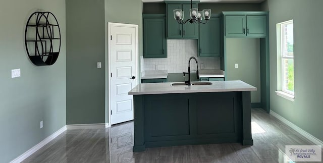 kitchen featuring a center island with sink, backsplash, sink, and hardwood / wood-style floors