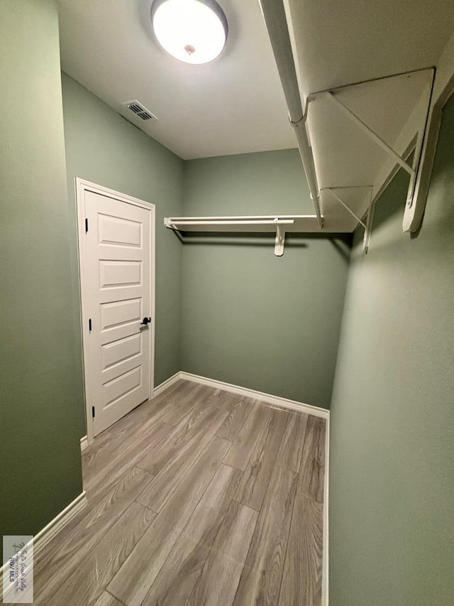 walk in closet with light hardwood / wood-style flooring