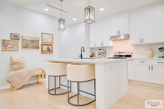 kitchen featuring white range, a kitchen island with sink, decorative light fixtures, light hardwood / wood-style floors, and white cabinetry