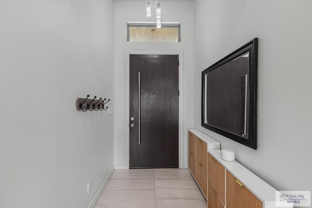 doorway to outside with light tile patterned flooring and baseboards