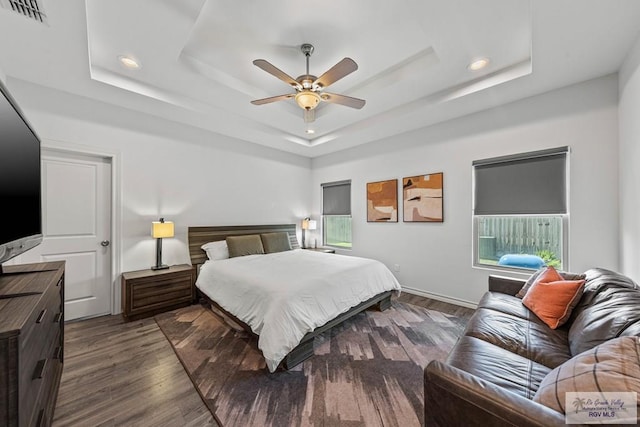 bedroom featuring visible vents, ceiling fan, a tray ceiling, and wood finished floors