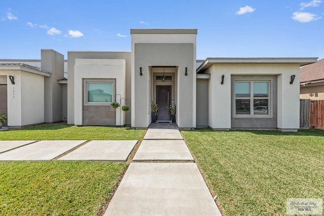 view of front of house with a front lawn, fence, and stucco siding