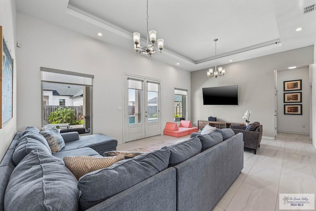 living room featuring recessed lighting, a tray ceiling, baseboards, and an inviting chandelier