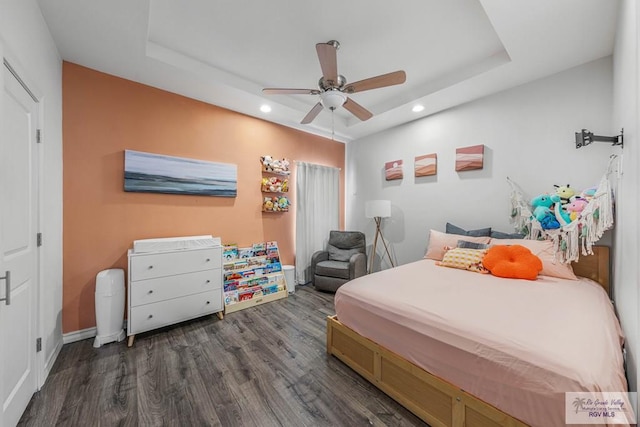 bedroom with wood finished floors, baseboards, a tray ceiling, recessed lighting, and ceiling fan