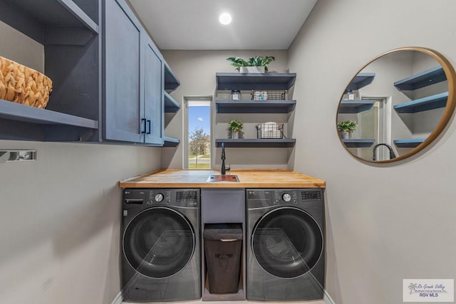 clothes washing area featuring a sink, cabinet space, baseboards, and separate washer and dryer