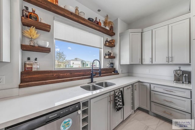 kitchen featuring gray cabinetry, open shelves, a sink, stainless steel dishwasher, and light countertops