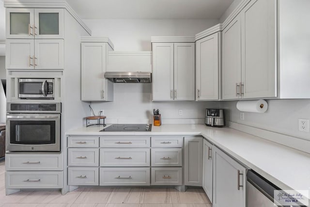 kitchen featuring stainless steel appliances, gray cabinetry, wall chimney exhaust hood, and light countertops