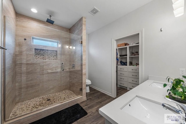 bathroom with a shower stall, wood finished floors, visible vents, and a sink