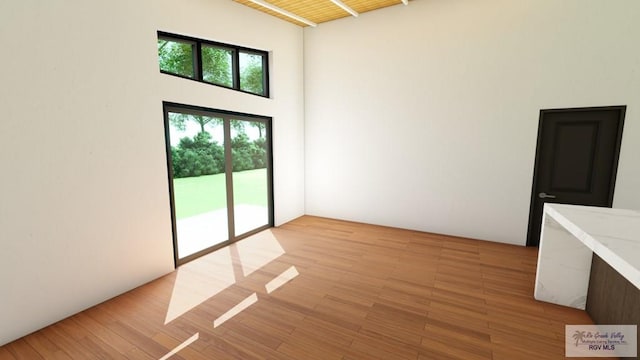 unfurnished room with light hardwood / wood-style flooring and a towering ceiling